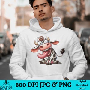 May include: A white hoodie with a cartoon image of a cow with a big tongue sticking out. The cow is black and white with a pink nose and a bell around its neck.