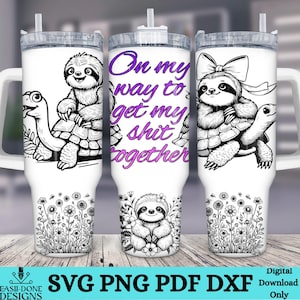 May include: A white tumbler with a black and white illustration of a sloth riding a turtle. The tumbler has a purple text overlay that reads "On my way to get my shit together".