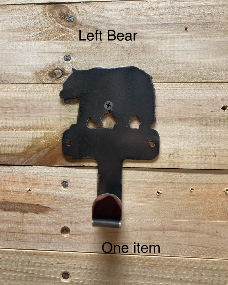 Op de afbeelding: Zwarte metalen beren-silhouet wandhaak met een enkele haak aan de onderkant. De beer kijkt naar links en de tekst "Left Bear" staat boven de beer. De tekst "One item" staat onder de haak.