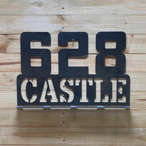 May include: Black metal house number sign with the number 628 and the word "CASTLE" underneath.