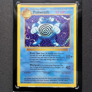 Puede incluir: Una carta coleccionable de Pokémon con Poliwrath, una criatura azul y blanca con forma de rana. La carta está en una funda protectora con las palabras "GAME FREAK" en la parte superior. La carta tiene texto que describe las habilidades.