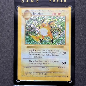 Puede incluir: Una carta de Pokémon Raichu en una funda protectora negra. La carta presenta una ilustración de Raichu amarillo y naranja con el texto "Raichu" y "80 HP". La carta es del set 14/102 y tiene el texto "GAME FREAK" en la parte superior.