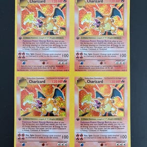 Puede incluir: Cuatro cartas coleccionables Pokémon Charizard. Cada carta presenta una ilustración de Charizard naranja llameante con alas azules, un borde amarillo y texto, incluyendo "Charizard 120 HP". Las cartas son de la serie Stage 2.