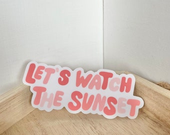 May include: Pink and white sticker with the text "Let's watch the sunset" in a retro font.