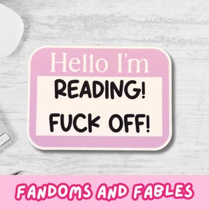 Peut inclure: Un autocollant rectangulaire aux coins arrondis, avec le texte "Hello I'm READING! FUCK OFF!" en noir sur un fond blanc et rose. L'autocollant comprend également le texte "FANDOMS AND FABLES" en rose.