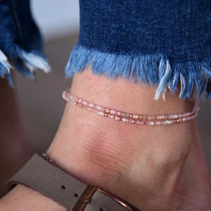 May include: A delicate anklet with two rows of small pink and gold beads.