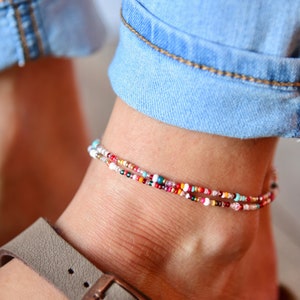 May include: A colorful beaded anklet with multiple strands of small beads in various colors, including red, white, blue, and green.