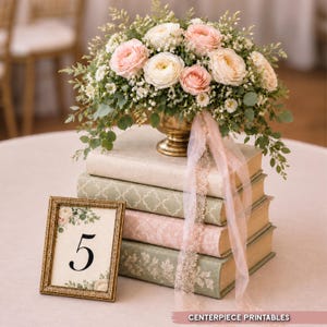 May include: A floral arrangement of pink and white ranunculus and greenery in a gold pedestal bowl, resting on a stack of four hardcover books. A gold-toned frame displays the number 5, decorated with floral accents and the text CENTERPIECE PRINTABLES.