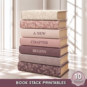 May include: A vertical stack of seven books with textured covers in shades of cream, dusty rose, and mauve. Three books feature floral patterns, while the middle three display the text A NEW CHAPTER BEGINS in a dark serif font. The pages are tan.