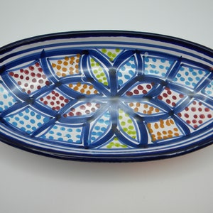 May include: An oval ceramic serving dish with a blue rim and a white background. The dish is decorated with a colorful geometric pattern of blue, green, orange, and red dots.