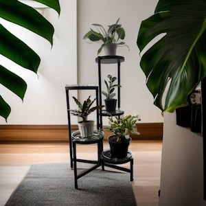 May include: A black metal plant stand with four tiers, each with a round glass top. The stand is decorated with a mosaic pattern. The stand is holding five potted plants, including a large green plant with white flowers, a small green plant with white flowers, a small green plant with red flowers, a small green plant with white flowers, and a small green plant with white flowers.