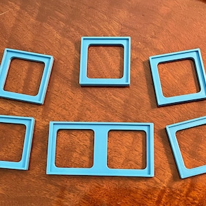 May include: Six blue plastic picture frames of various sizes. The frames are arranged in a pattern on a wooden surface.