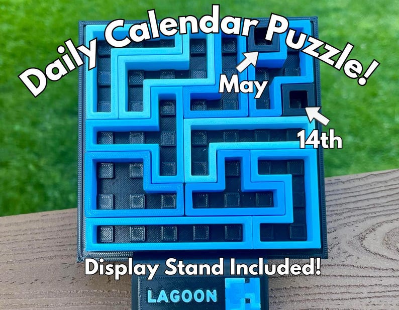 Może przedstawiać: Codzienna układanka kalendarzowa z labiryntem w odcieniach niebieskiego i czarnego. Tekst "Daily Calendar Puzzle!" jest wyświetlany u g&oacute;ry, ze strzałkami wskazującymi "May 14th". Podstawa wyświetlacza na dole zawiera napis "Display Stand Included!" i "LAGOON".