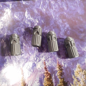 May include: Four gray plastic valve stem caps with a design of a helmet on top.