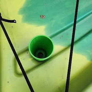 Op de afbeelding: Een groene kunststof aftapplug voor een kajak of kano. De plug wordt in een rond gat in de bodem van de boot gestoken.