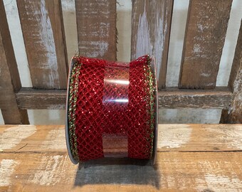 May include: A spool of red mesh ribbon featuring a glittery texture and a metallic gold edge. The ribbon is wrapped around a circular core and secured with a clear plastic band, showcasing a wide, open-weave design with a vibrant, reflective finish.