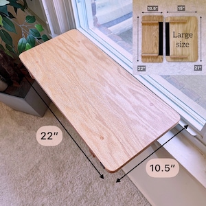 K&ouml;nnte beinhalten: Ein Holz-Fensterbrett, 56 cm lang und 27 cm breit, montiert auf einem Fenstersims. Das Brett ist aus hellem Holz mit nat&uuml;rlicher Maserung. Das Brett ist als Katzenliege oder kleiner Pflanzenst&auml;nder gedacht.