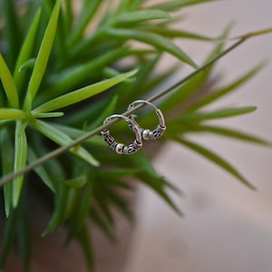 May include: A pair of silver hoop earrings with a textured design. The earrings are small and delicate, and they are perfect for everyday wear.