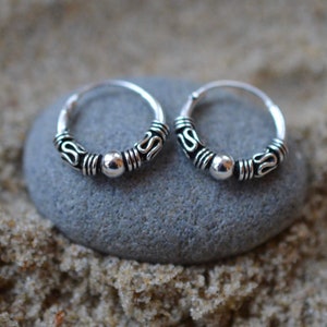 May include: A pair of silver hoop earrings with a beaded design. The earrings are small and delicate, and they would be perfect for everyday wear.