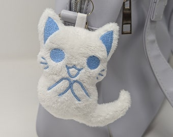 May include: A white plush cat keychain with blue embroidered details, attached to a silver zipper pull on a light purple bag.