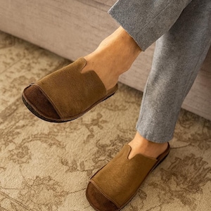 Handmade leather slip-on mules crafted in timeless black and cream colors. Made from genuine leather with a rustic, natural texture, these unisex shoes combine comfort and durability for everyday wear. Available in EU sizes 38–43, but please note: sizing runs small (example: EU 38 fits closer to EU 40). Perfect for summer outfits with jeans or shorts, they are stylish, breathable, and versatile for men and women who value artisan quality.