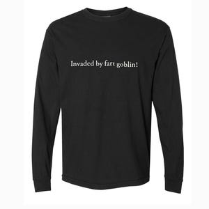 May include: Black long-sleeve shirt with the white text "Invaded by fart goblin!" centered on the front. The shirt has a crew neck and long sleeves. The fabric appears to be a soft, comfortable material.
