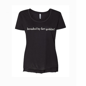 May include: Black scoop neck t-shirt with the text "Invaded by fart goblin!" in white. The shirt has short sleeves and a slightly curved hemline. The text is centered on the chest.