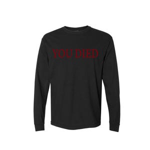 May include: Black long-sleeve shirt with the words "YOU DIED" printed in red across the chest. The shirt has a crew neck and long sleeves. The text is in a bold, sans-serif font.