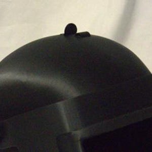 May include: Black helmet with a visor and a small black detail on the top.