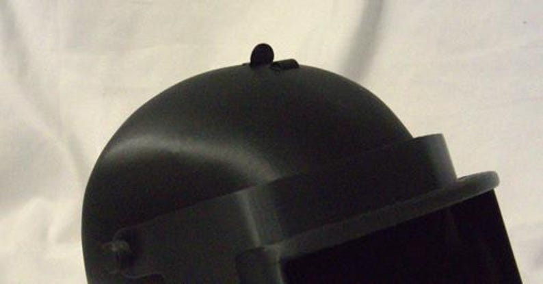 May include: Black helmet with a visor and a small black detail on the top.