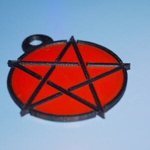 May include: A red pentagram charm with a black outline. The charm is a circle with a five-pointed star inside.