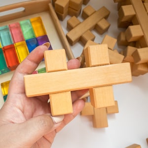 Könnte beinhalten: Ein Satz Holzblöcke in Form eines Kreuzes. Die Blöcke sind hellbraun und haben eine glatte Oberfläche. Die Blöcke sind in einem Muster angeordnet, das einem Kreuz ähnelt.