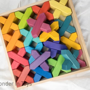 May include: Wooden puzzle with colorful, interlocking pieces in a square wooden tray. The pieces are painted in various colors, including red, orange, yellow, green, blue, and purple. The puzzle is designed for children.