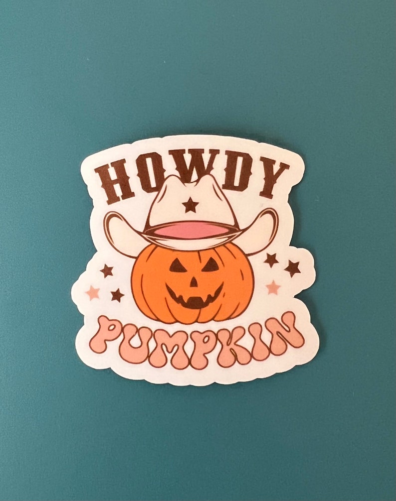 May include: A sticker featuring a cartoon pumpkin wearing a cowboy hat. The pumpkin is orange with a carved face. The text "HOWDY PUMPKIN" is written above and below the pumpkin in brown and pink.