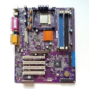 May include: A purple computer motherboard featuring a central processor, an orange heatsink, multiple white PCI slots, blue and black RAM slots, and various integrated components including a VIA chipset and a silver circular CMOS battery.