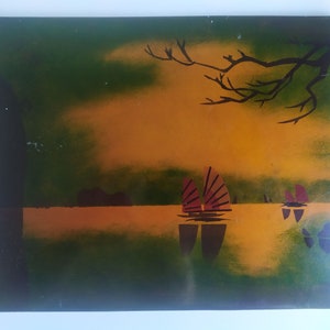 Peut inclure: Une peinture représentant un coucher de soleil sur une étendue d'eau avec trois voiliers au loin. Le ciel est un dégradé d'orange, de jaune et de vert, et l'eau est d'un bleu foncé. La peinture est encadrée d'un cadre noir.
