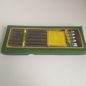 May include: A box of six stainless steel knives with green and yellow packaging. The box has the text "Svenskt Stål Knivar" and "AB. Gense, Eskilstuna, Sweden".