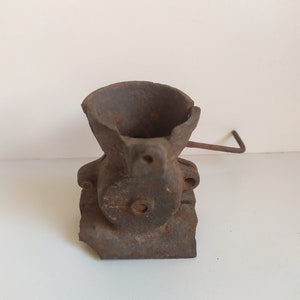 May include: A vintage cast iron hand crank grinder with a worn, rusty finish. The grinder has a small hopper and a crank handle.