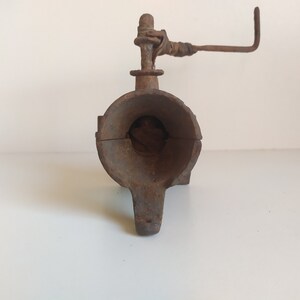 May include: A rusty cast iron hand crank meat grinder with a handle and a large opening for inserting meat.