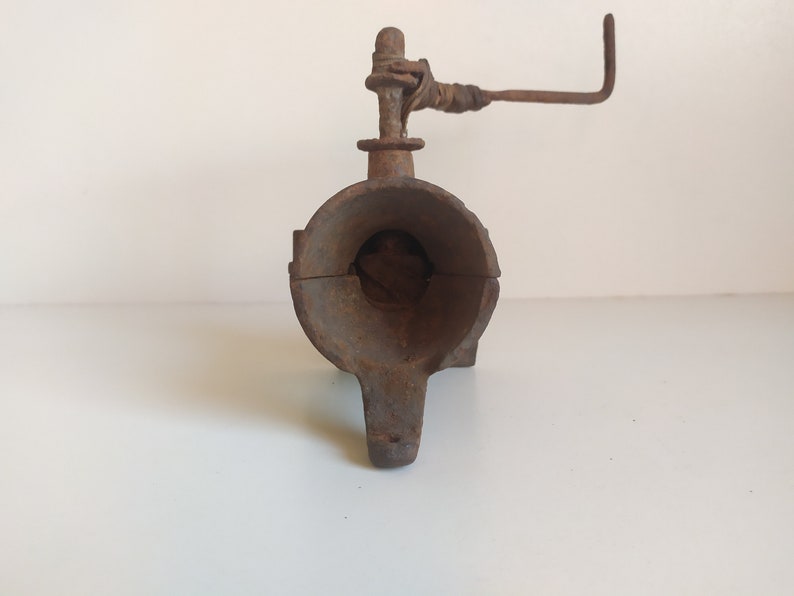 May include: A rusty cast iron hand crank meat grinder with a handle and a large opening for inserting meat.