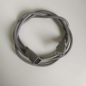 Peut inclure: Un cordon d'alimentation gris avec une prise à trois broches à une extrémité et une prise à quatre broches à l'autre extrémité.