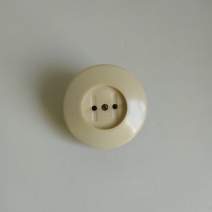 May include: A white plastic electrical outlet cover with three holes.