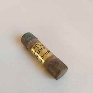 May include: A brown and gold fuse with the text "MH "C" 1TN1 25A 60C 85C B1C" printed on it.