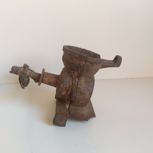 May include: A vintage cast iron hand-crank coffee grinder with a worn brown finish. The grinder has a hopper, a crank, and a base.