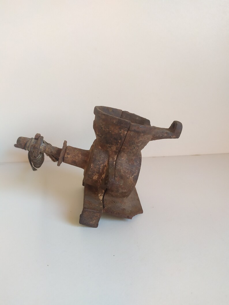 May include: A vintage cast iron hand-crank coffee grinder with a worn brown finish. The grinder has a hopper, a crank, and a base.