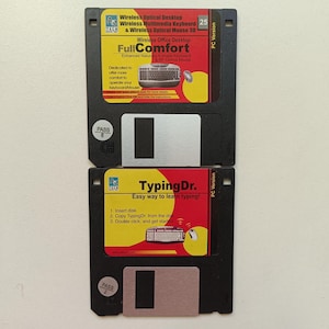 May include: Two black 3.5-inch floppy disks stacked vertically. The top disk features a red and yellow label for A4 Tech Wireless Optical Desktop with keyboard and mouse graphics. The bottom disk has a red and yellow label for TypingDr.