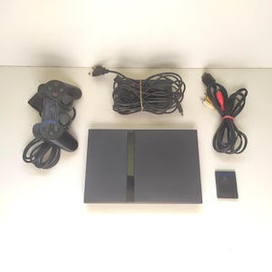 Consola Sony PlayStation 2 Slim vintage (PS2, mando OEM, tarjeta de memoria y juego FIFA 08) en muy buen estado.