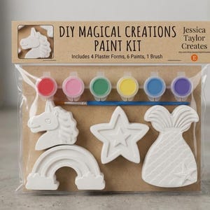 May include: A DIY Magical Creations paint kit in a clear plastic bag containing four white plaster forms shaped like a unicorn, a star, a rainbow, and a mermaid tail, along with six small paint pots in red, pink, green, yellow, blue, and purple, and one brush.