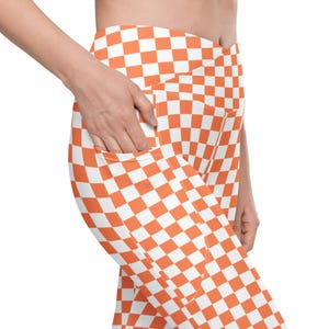 May include: Orange and white checkered leggings with side pockets. The leggings are made of a stretchy, comfortable fabric and are perfect for working out or running errands.