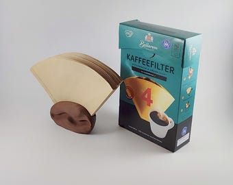 May include: A brown ceramic coffee bean-shaped filter holder with a stack of beige paper coffee filters. A teal box of "KAFFEEFILTER" coffee filters is next to the holder. The box has a coffee cup graphic and the number "4".